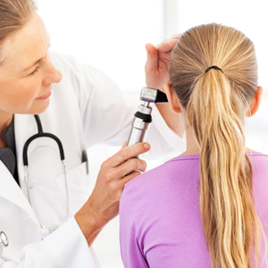 Doctor examining girl's ear with an otoscope 