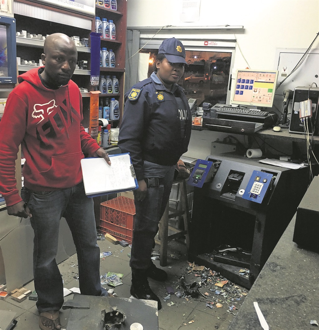 Constable Sihle Khambule (left) and Sergeant Khulekani Ncube inspect the damage to the shop.  Photo by SAPS 