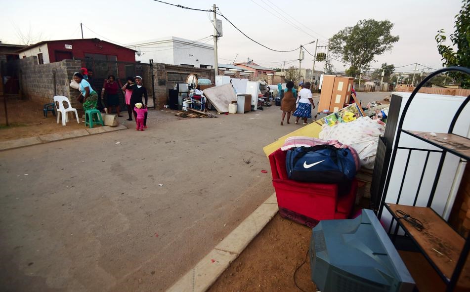 WHAT NOW? Two new ‘owners’ are stranded outside with their furniture in the street waiting to occupy the property. The seller faces fraud charges. Photo by Everson Luhanga