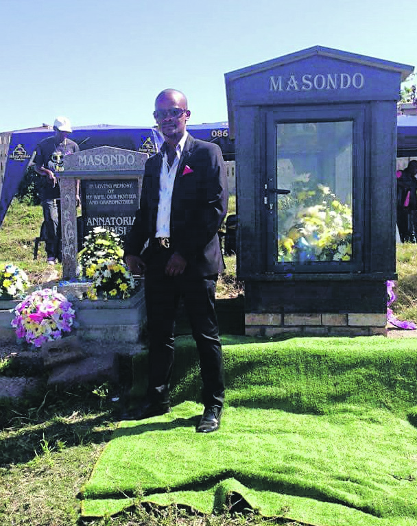 Sphamandla Masondo stands next to his father’s tombstone. 