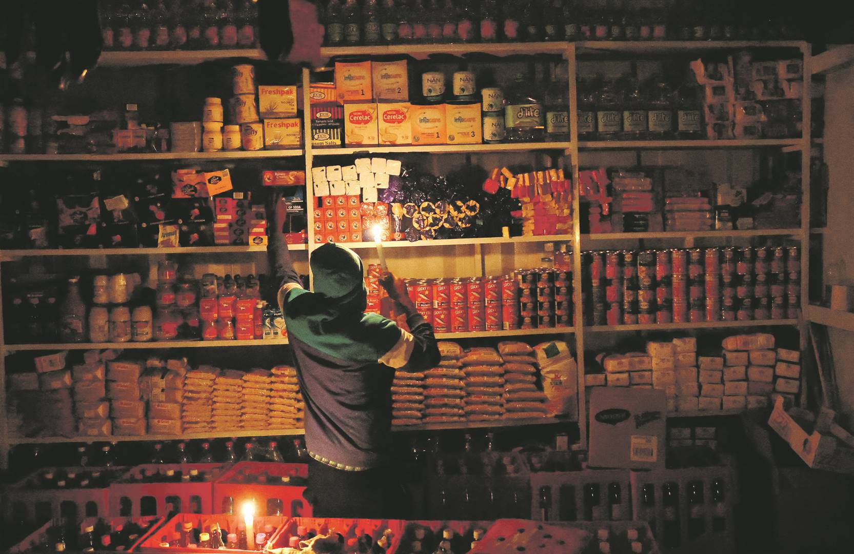 energy crisisA shop owner picks an item off the shelf for a customer by candlelight, during one of the country’s many power outages. Eskom has been battling to keep the lights on for several years due to more breakdowns at its ageing coal-fired plants. The introduction of clean energy could alleviate the power shortages, while easing the climate crisis. Photo: siphiwe sibeko / reuters