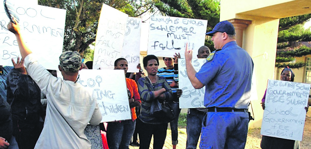 A cop tries to reason with protesting parents outside Settlers’ Primary School in Walmer yesterday.                                                        Photo by Chris Qwazi 