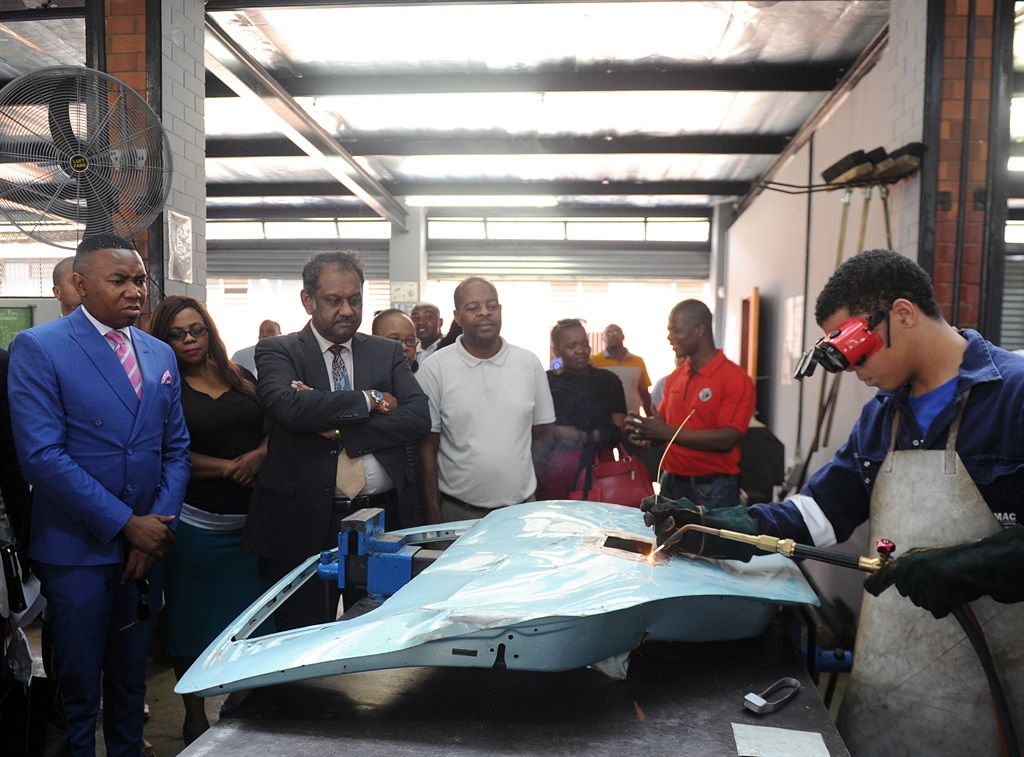 Department of Higher Education and Training deputy minister Mduduzi Manana (left in blue suit) watching one of the West Ridge High School pupil Camerone Ryan fixing a car door.   Photo by Jabulani Langa 
