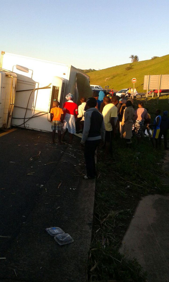 Some of the residents stand near the chicken truck after it overturned on the N2 in Hibberdene.  Photo supplied 