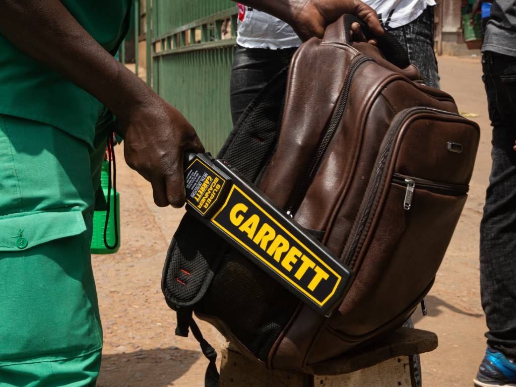 A security officer checks a bag of passenger as Po