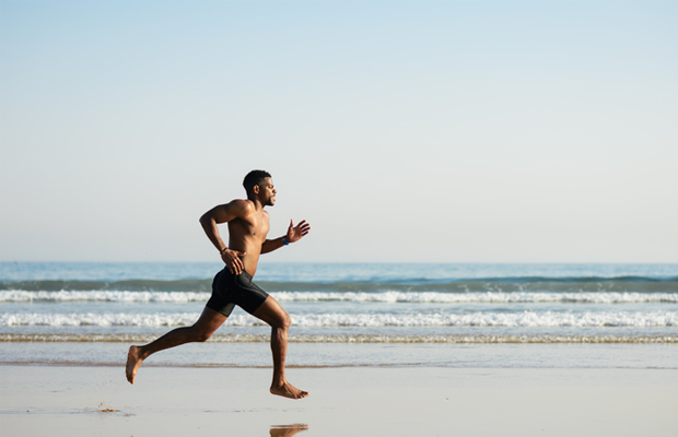 A man running barefoot on the beach