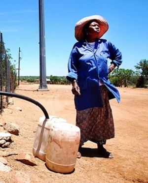 A woman collects water from a water tank.