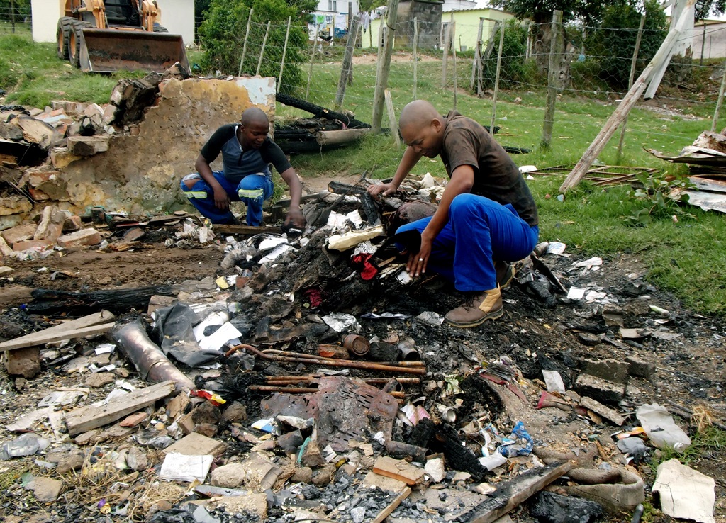 Relative Mzimkhulu Feni (right) and his friend, Phathuxolo Tukulu, inspect the damage after the Nobebes’ house caught fire.                                               Photo by Buziwe Nocuze 