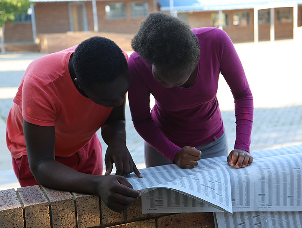  Grade 12 pupils anxiously scour a newspaper for their matric results.  