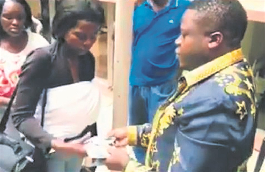 A screen grab from a Facebook video shows the apparent mystery moreki dishing out money to queuing mums with their babies. 