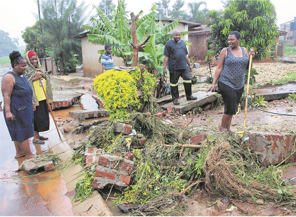 Elsi Masindi (right) and her neighbours look at the damage caused by the heavy rain on Saturday.                Photo by Armando Chikhudo   