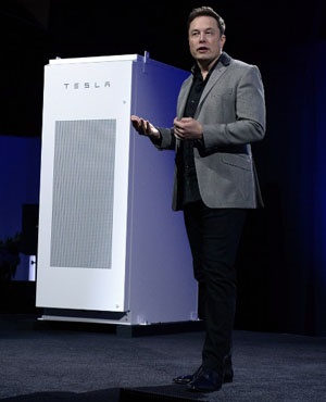 Elon Musk, CEO of Tesla, with a Powerpack unit the background unveils suit of batteries for homes, businesses, and utilities at Tesla Design Studio, Hawthorne, California. 