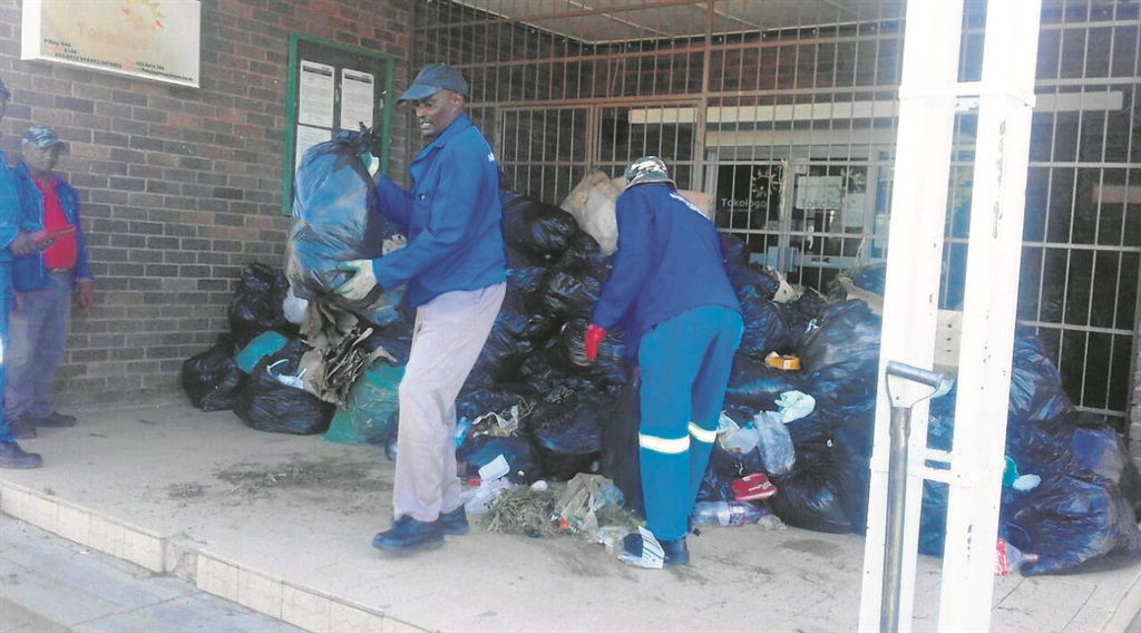 Tokologo municipal workers remove bags dumped in front of the entrance to the offices. 