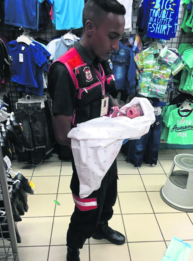 Paramedic Devan Perumal holds the baby boy who was delivered in a Pep store in the Verulam CBD.   