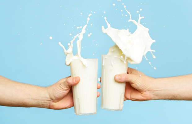 Two people holding glasses of milk