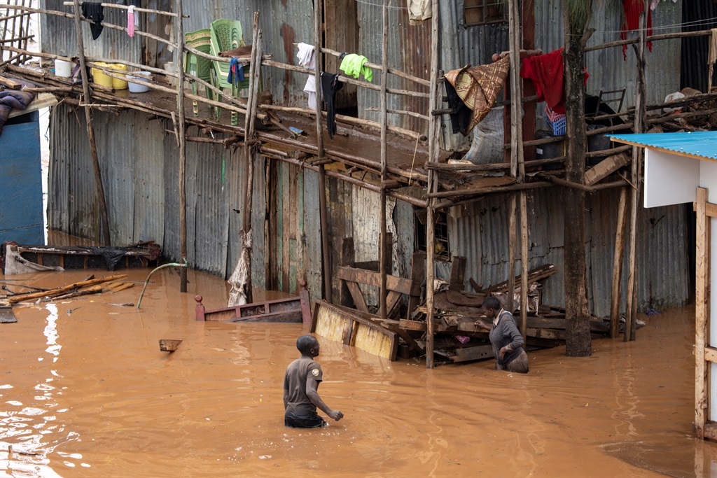 Residents of Mathare slum walk through flooded waters following heavy downpours in the capital, Nairobi, on 24 April 2024. Storms and flash floods wreaked devastation across the Kenyan capital, Nairobi, on 24 April 2024. (Simon Maina/AFP)