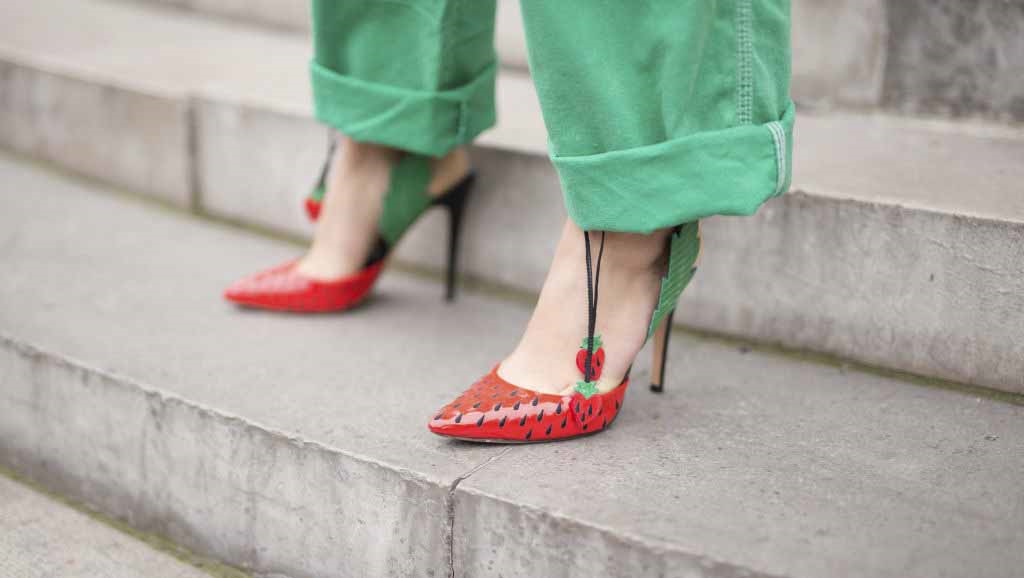 A woman wears a pair of shoes with a strawberry design