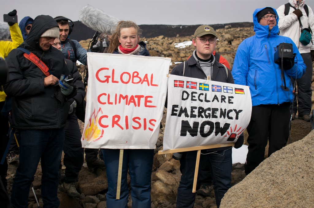 People hold up signs as a monument was unveiled at the site of Okjokull, Iceland's first glacier lost to climate change. (Jeremie Richard, AFP)