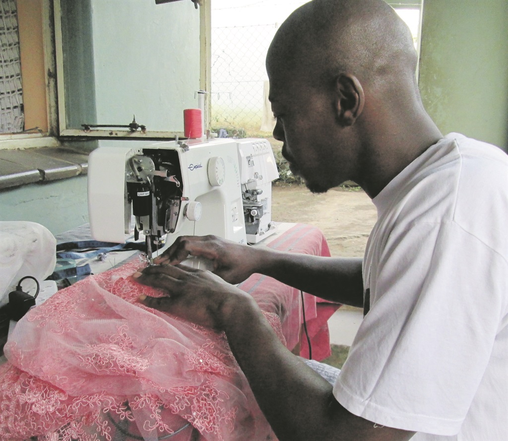 Mazwi Mkhize makes a dress for one of his clients. Photo by Mbali Dlungwana
