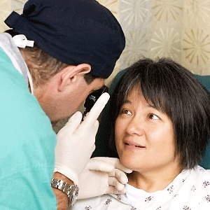 A doctor inspects a patient's eye with the use of an ophthalmoscope.