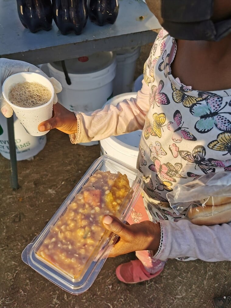 A child with a meal prepared by volunteers