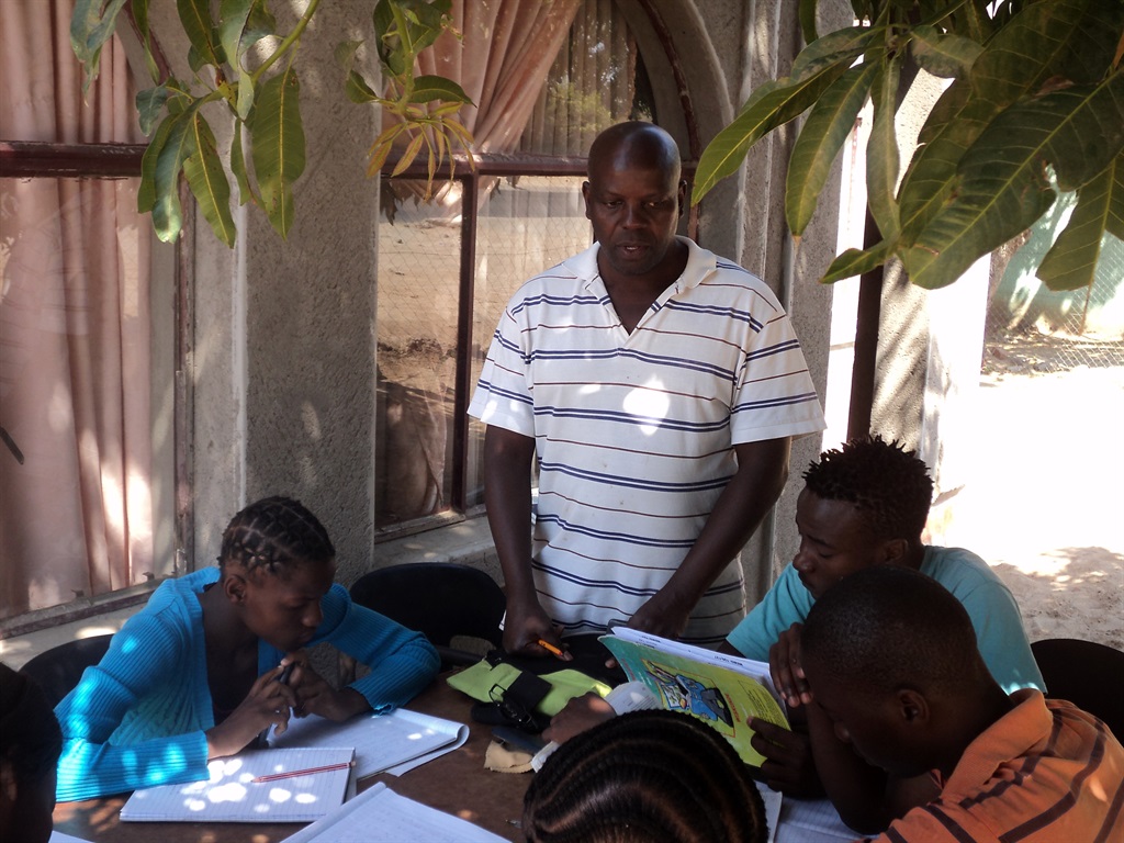 Jerry Mbowane gives maths and science classes to pupils, from under the tree in his yard in 2014. Picture: Yvonne Silaule