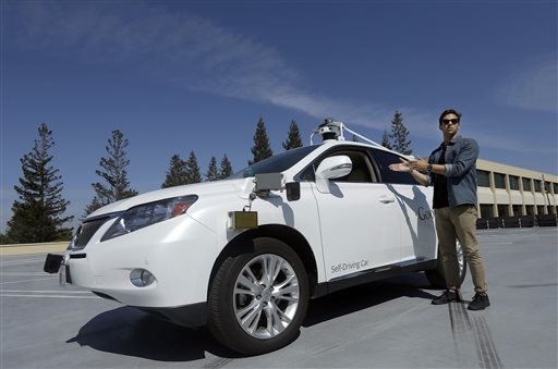 <b> SELF-DRIVING CARS: </b> Brian Torcellini, Google team leader of driving operations, poses next to a self-driving car at a Google office in Mountain View, California. <i>Image: AP /Jeff Chiu</i>.<i> Image: Volkswagen </i>