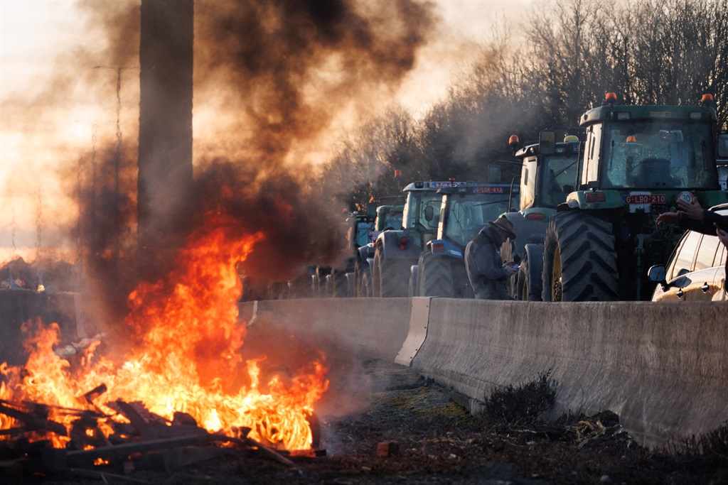 Tractors pass by a fire lit by farmers during a fa