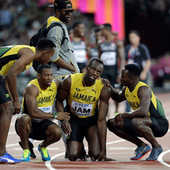 Usain Bolt is consoled by his teammates (AP)
