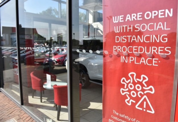 Signs with social distancing guidelines in the window of a reopened Toyota car dealership showroom. Image: John Keeble/Getty Images