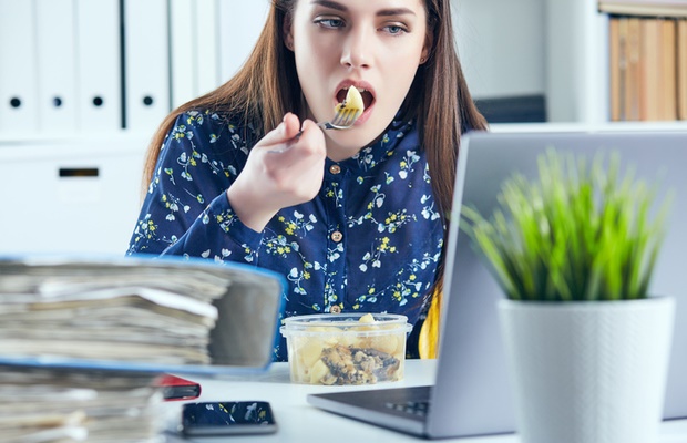 woman eating packed lunch at her desk 
