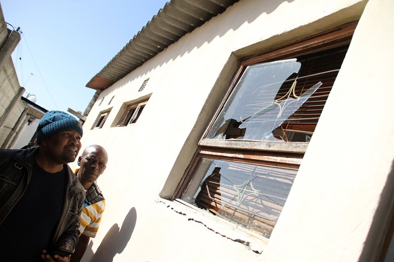 Ward 98 councillor Anele Gabhuza and Masixole Mgutyowa inspect the damage after groups of people from Ndlovini broke the windows of his housePhoto by Lindile Mbontsi