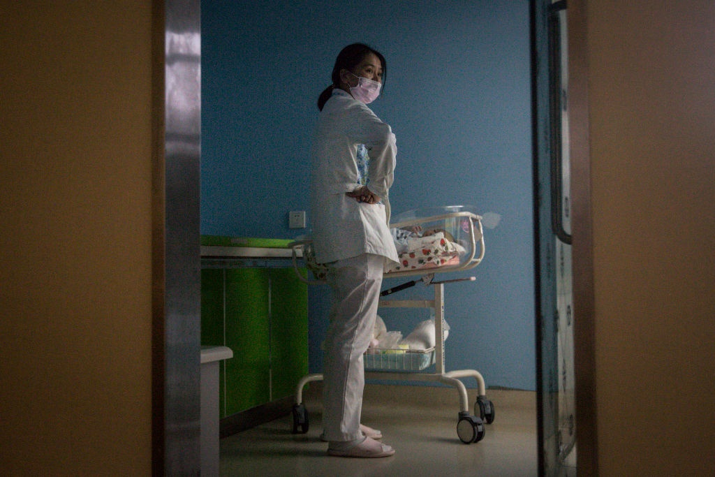 A maternity nurse wears a mask as she cares for a newborn at a hospital in Wuhan, Hubei, China. 