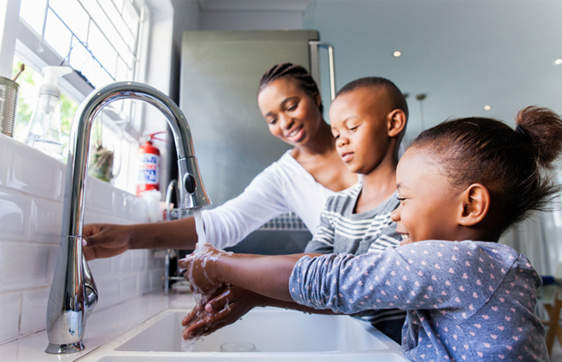 family washing hands at kitchen sink
