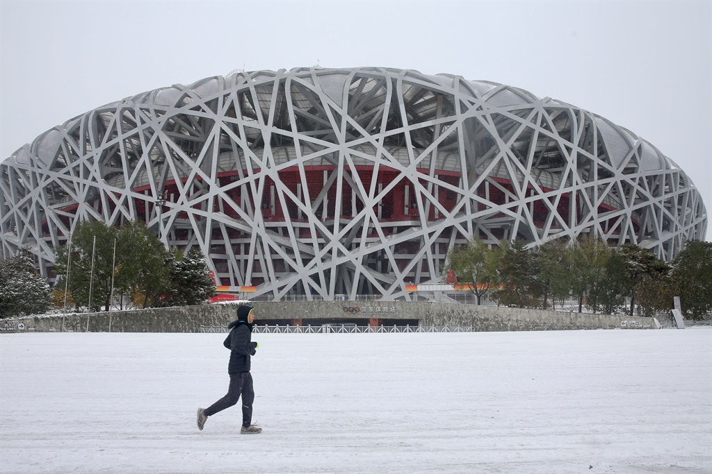 BEIJING, CHINA - NOVEMBER 07: A citizen runs past the National Stadium, also known as the Birds Nest, after a snowfall on November 7, 2021 in Beijing, China. (Photo by Yi Haifei/China News Service via Getty Images)