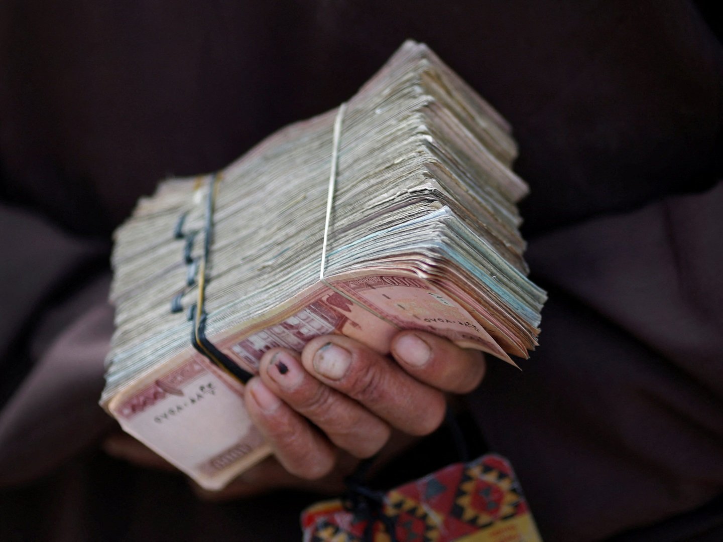 A money changer holds a stack of Afghan currency on a street in central Kabul. Tim Wimborne/ Reuters