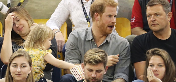 A toddler sneaking some of Prince Harry's popcorn. (Photo: Getty Images)