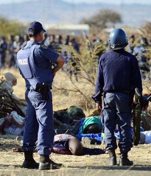 Police stand over the bodies of the striking miners who got shot in August 2012