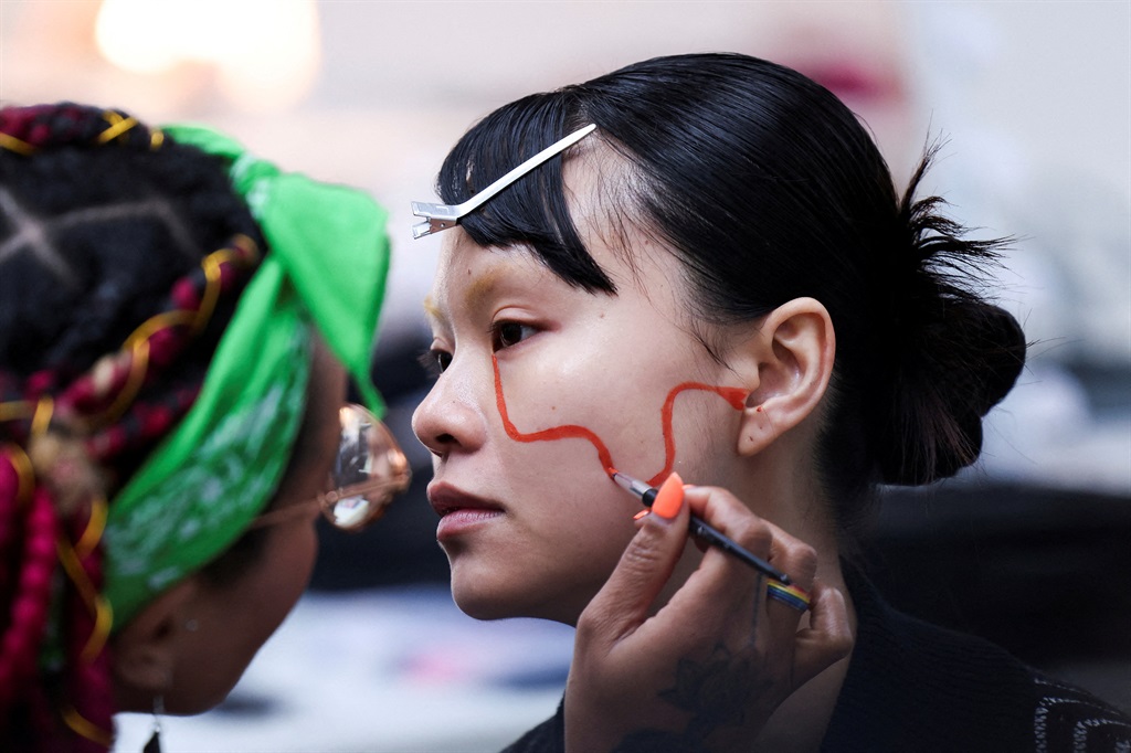 A model has her face painted backstage for Ones to