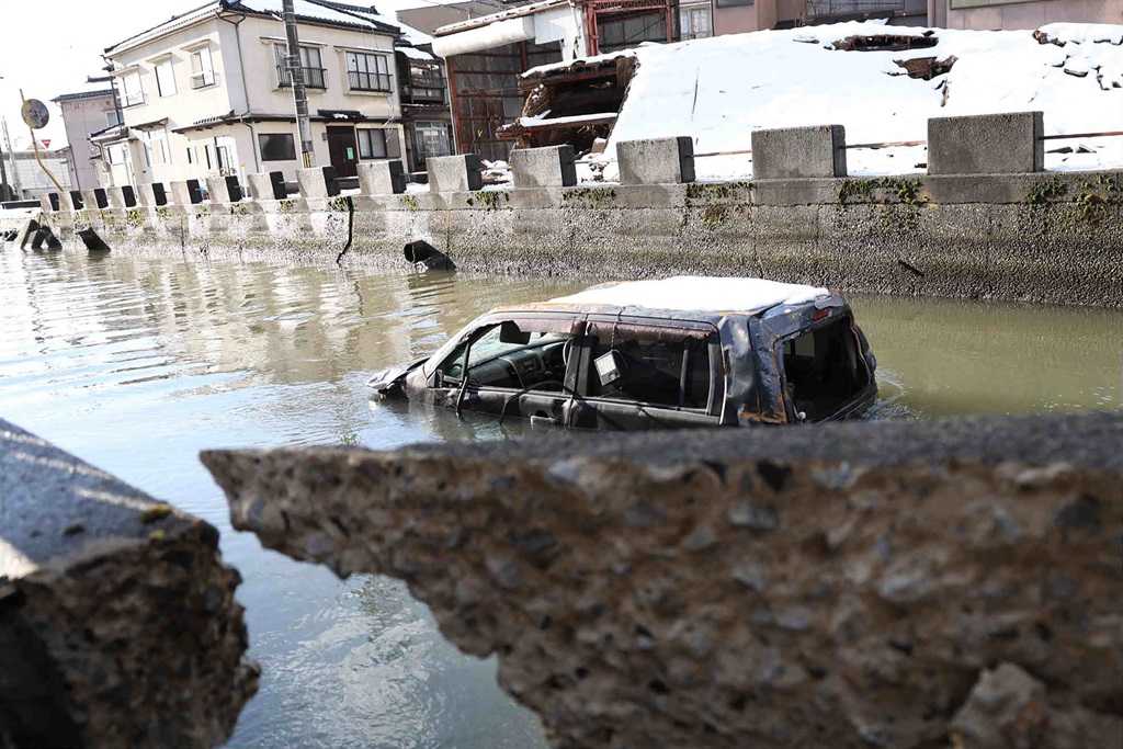 A vehicle believed to be washed away by the tsunami sits in water next to damaged buildings in the disaster-hit city of Noto, Ishikawa prefecture, on 9 January 2024, after a major 7.5 magnitude earthquake struck the Noto region in Ishikawa prefecture on New Year's Day. 