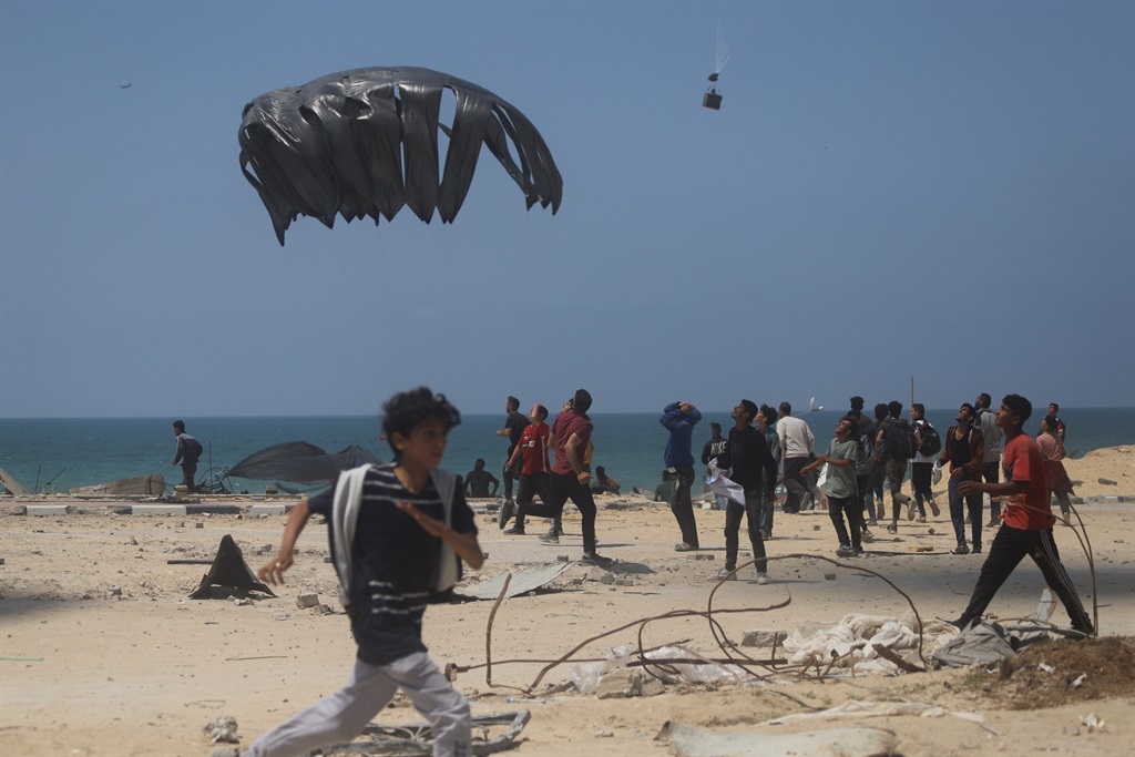 Palestyne loop nader om hulp te ontvang nadat humanitêre hulp in bokse uit ’n vliegtuig op noordelike distrikte afgelaai is. Foto: Getty Images/Anadolu