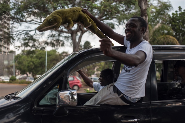 A Zimbabwean holds a crocodile soft toy as he celebrates from a car the arrival of Zimbabwe's ousted vice president Emmerson Mnangagwa, who is referred to as the "crocodile". (Stefan Heunis/AFP)