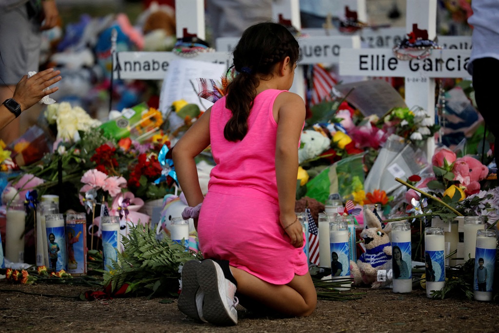 A girl pays her respects at a memorial site at Robb Elementary School, where a gunman killed 19 children and two adults in Uvalde, Texas, in the US. Victims of the May mass shooting have filed a $27 billion (R467 billion) class action against public entities and officials, seeking damages for ongoing trauma. Photo: Marco Bello / Reuters