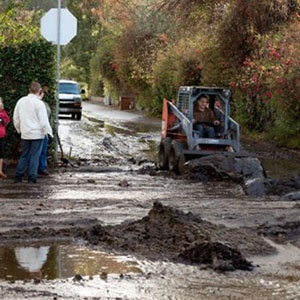 Residents watch as mudslide debris is cleared up in Montecilo