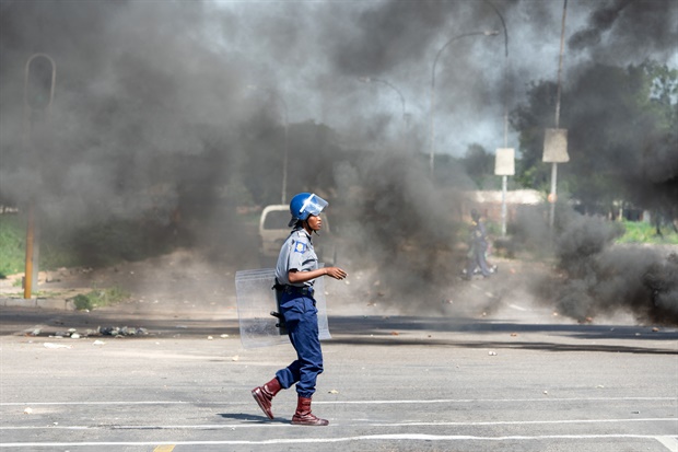 A police officer walks amid smoke during a
"stay-away" demonstration against the doubling of fuel prices in
Emakhandeni township, Bulawayo. (Picture: AFP)

