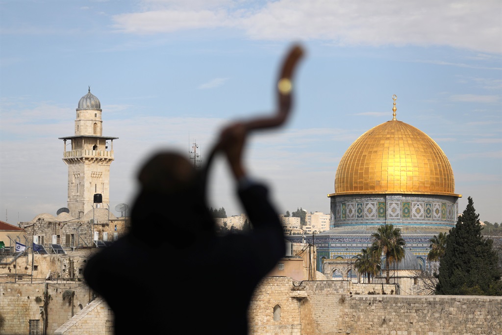 A man is silhouetted while he blows a Shofar, a ram horn, in Jerusalem's Old City on December 10 2017. The Dome of the Rock, located on the compound known to Muslims as Noble Sanctuary and to Jews as Temple Mount, is seen in the background. Picture: Ammar Awad/Reuters