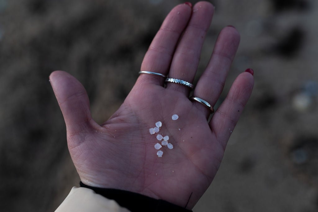 An agent of the Local Police and a coast guard make a collection of pellets from the sand, in Illa de Arousa, on January 4, 2024, in Pontevedra, Galicia, Spain. The pellets are small plastic balls of less than five millimeters in size that are used to manufacture plastic products, because of their small size and light weight, it is almost impossible to clean them up once they are scattered on the beaches. 