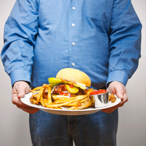 Overweight man holding a calorie-rich plate
