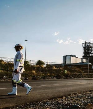 A mine worker walks past the Marikana platinum mine, operated by Lonmin Plc, in Marikana, South Africa, on Monday, Nov. 9, 2015. Lonmin's warning that it may be forced out of business shows just how dire the situation has become for some of the world
