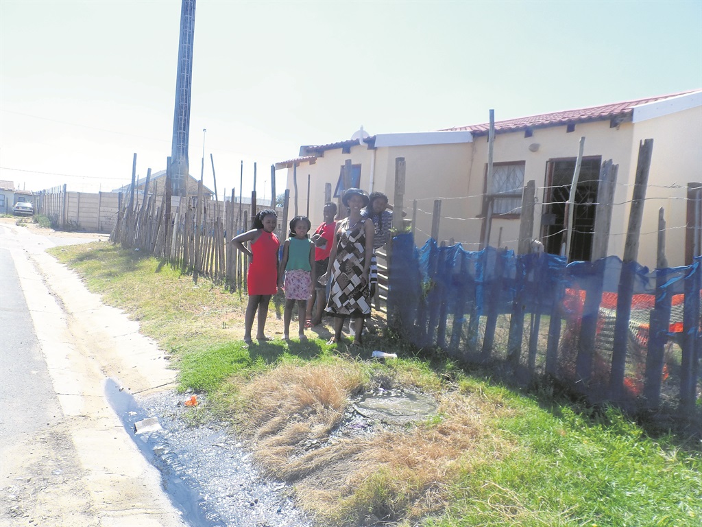 Nondumiso Layiti and the children who live with her stand in front of her house where sewage gushes out of the manhole.         Photo by Joseph Chirume